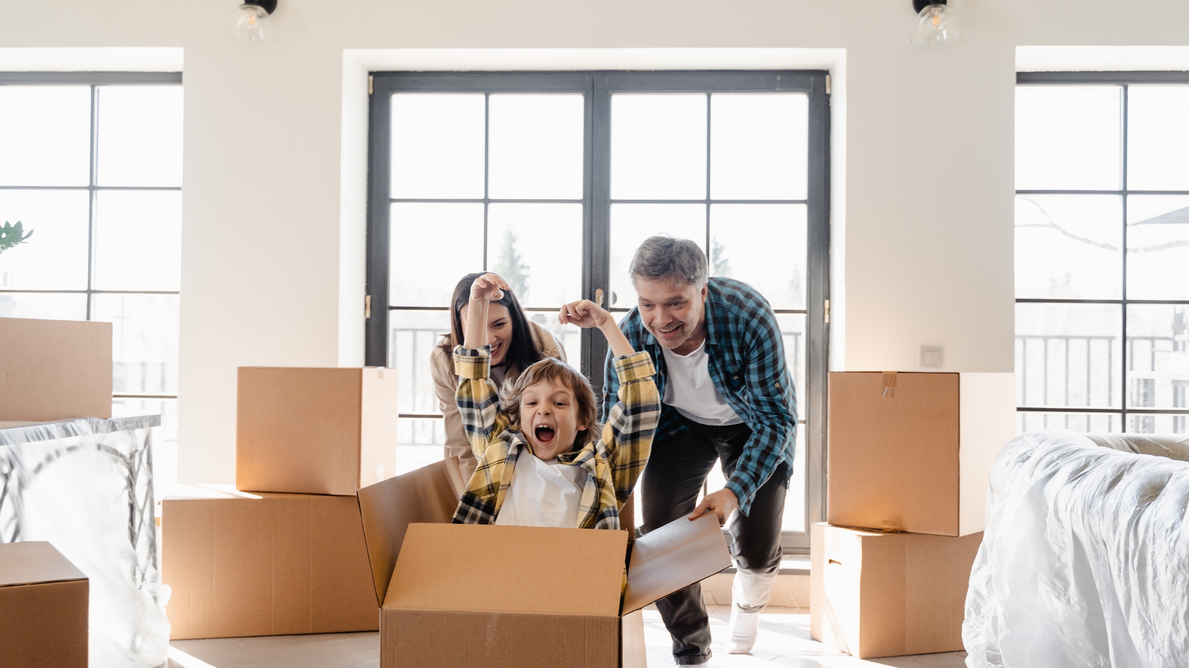 A child laughs as they are pushed in a packing box along the floor of their new home in Raleigh by their parents.