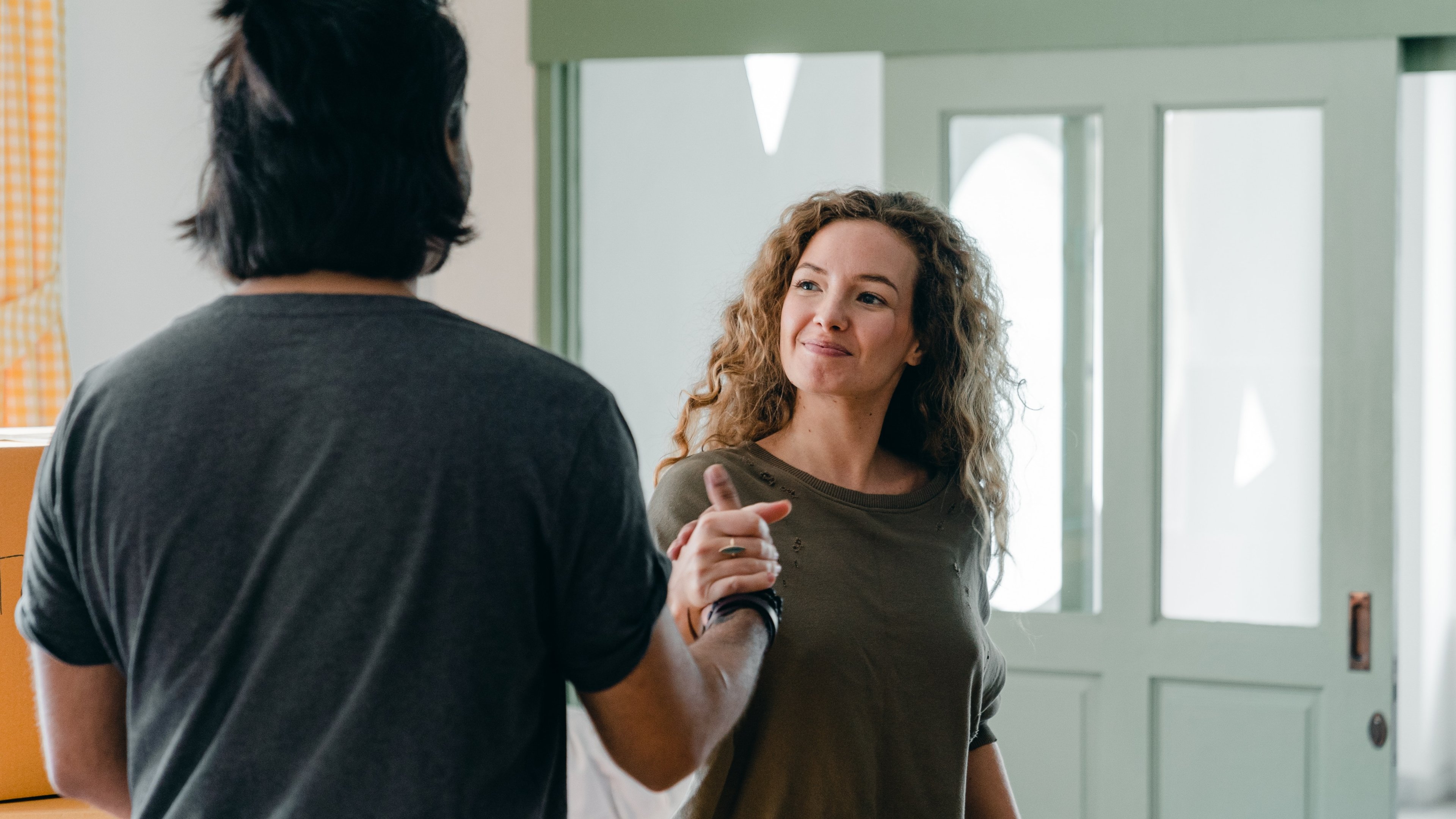 Image of two first time homebuyers with linked hands standing just inside their new front door