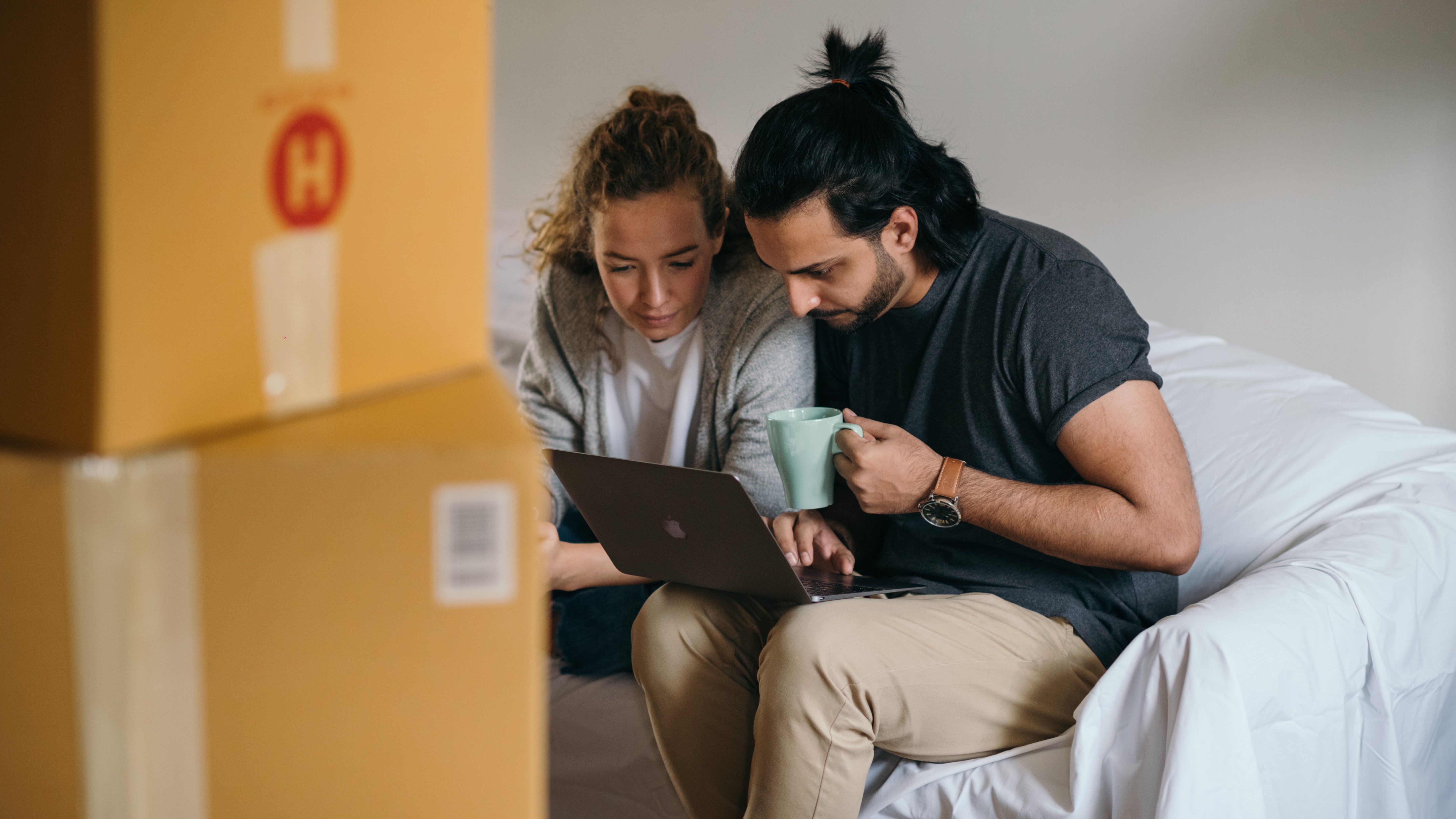 two would be first time homebuyers look. at a laptop as they read about tips to boost their credit scores